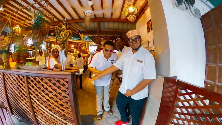 Staff behind a carved wooden bar in a Stone Town restaurant